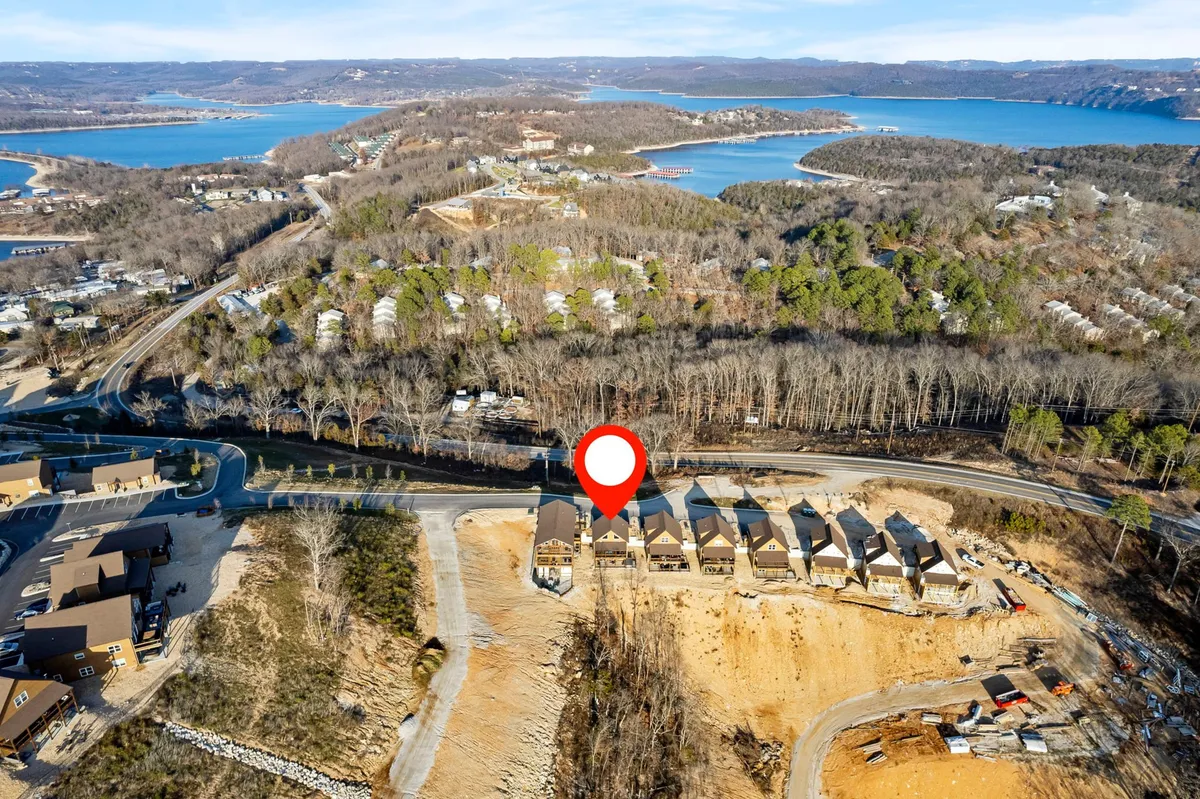 This striking exterior shot showcases newly constructed homes nestled among lush greenery, with a clear view of Table Rock Lake and the surrounding natural landscape. The image captures winding roadways, mature trees, and the tranquil expanse of water, perfectly illustrating the close proximity to nature and outdoor adventure.