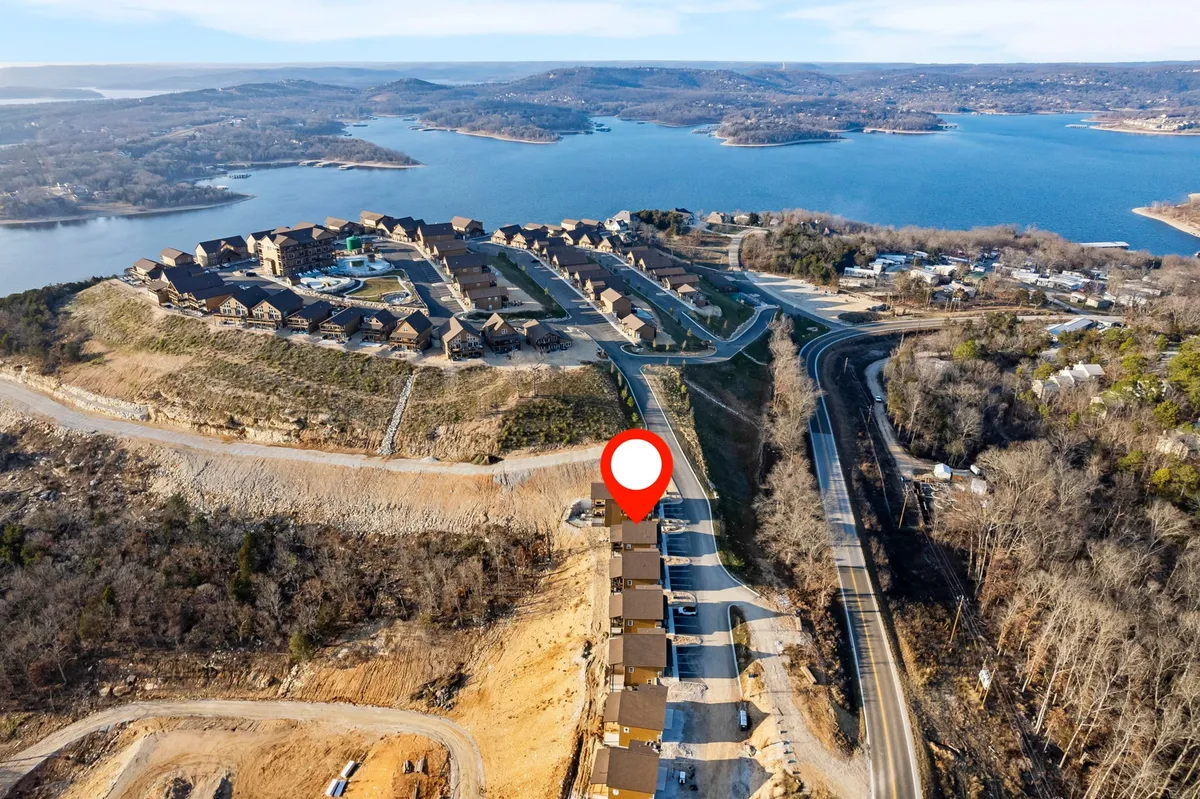 A serene vista of waterfront properties along Table Rock Lake, with the surrounding landscape and gentle hills creating a peaceful, natural setting. The calm water and open skies evoke a sense of relaxation and endless outdoor possibilities.