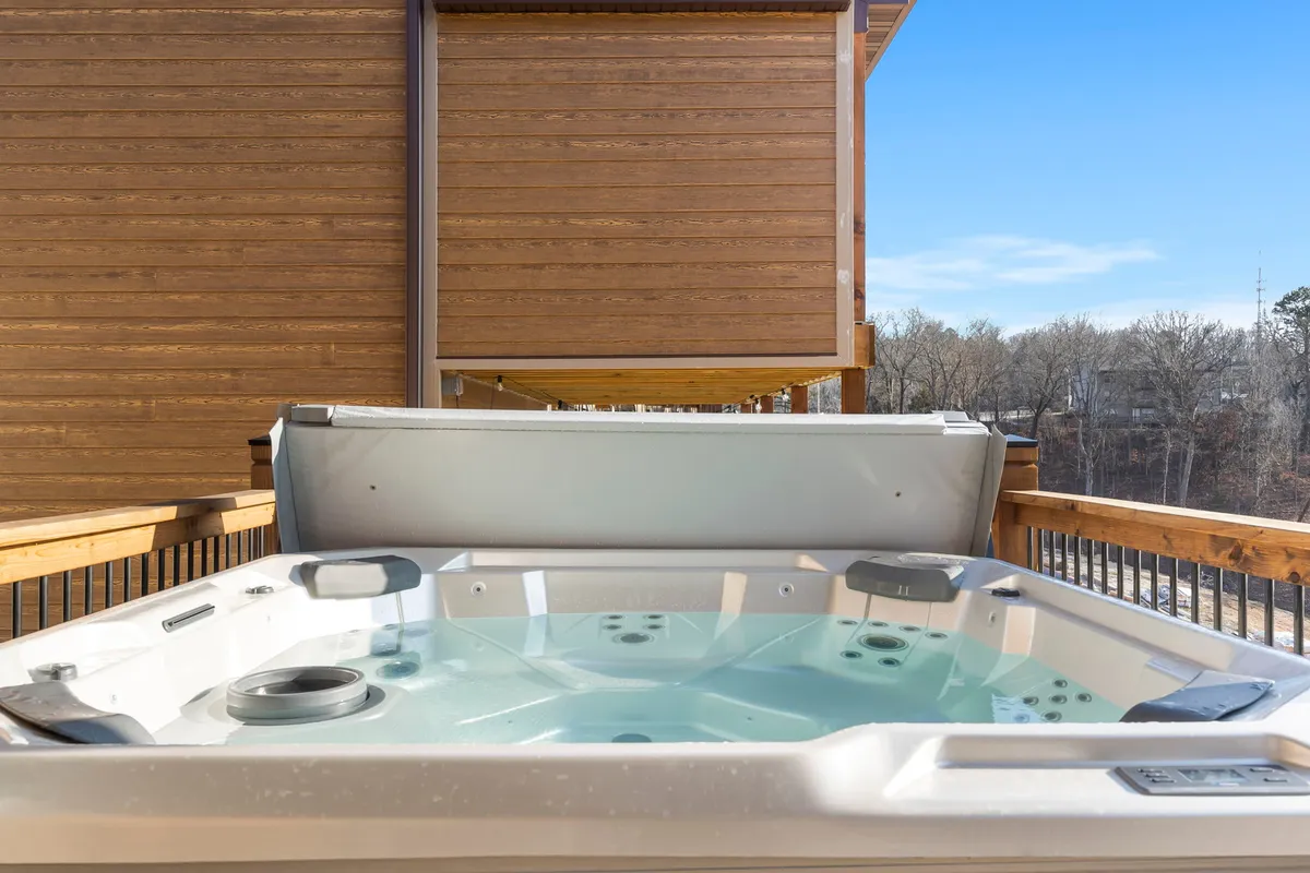 An inviting exterior view of a private hot tub situated on a wooden deck, surrounded by lush nature, evoking a sense of tranquility and seclusion. The space is ideal for stargazing or soaking in the fresh mountain air.