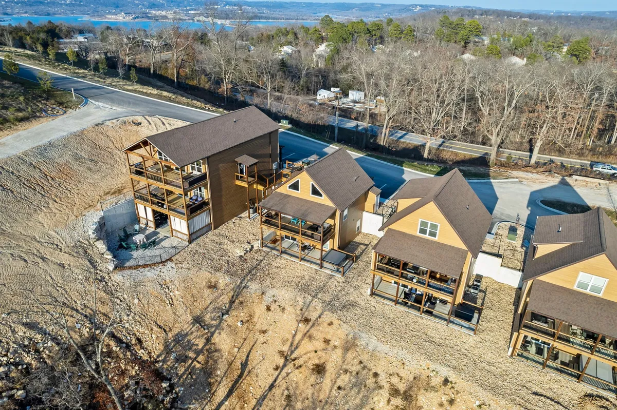 Multi-story homes are set against a tranquil landscape, with a road winding toward the property and scenic views that hint at nearby natural attractions such as Table Rock Lake. The setting is peaceful, inviting, and perfect for exploration or retreat.