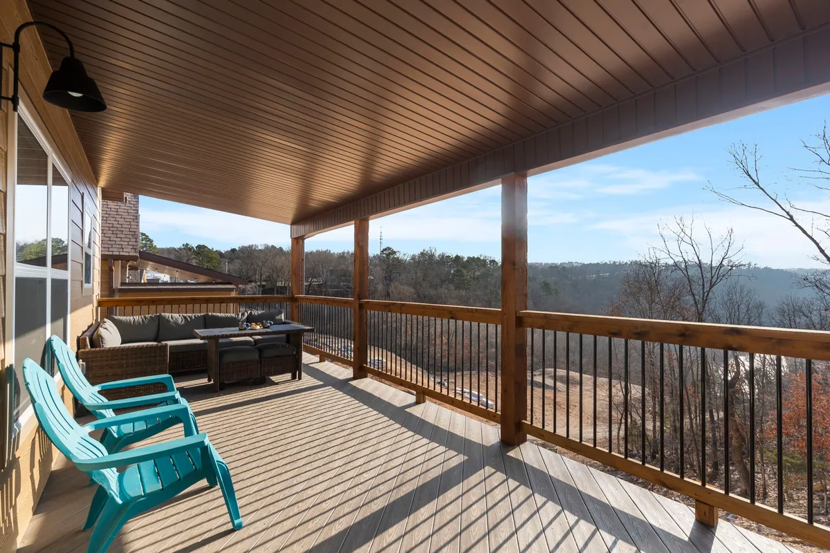 An inviting exterior deck with comfortable outdoor seating and a coffee table, overlooking a scenic woodland view. The area is ideal for morning coffee, evening cocktails, or simply savoring the natural beauty of the Ozarks from the comfort of home.