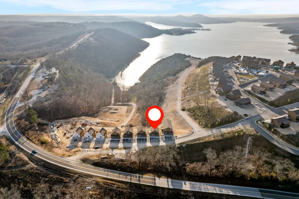 A scenic exterior view showcasing a row of resort-style houses nestled along the lake, with mountains in the distance and quiet roads winding through the landscape. The image conveys serenity and ample space, ideal for lakeside walks and easy outdoor exploration with pets.