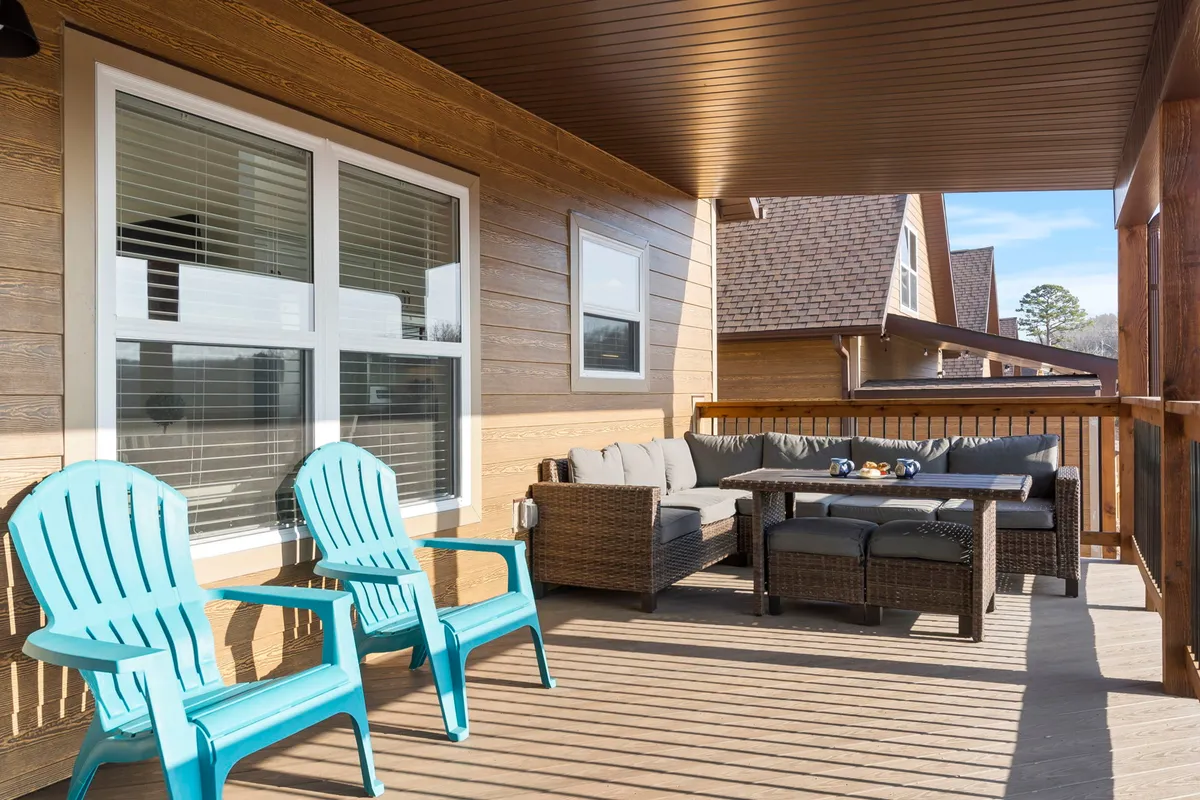 This image features a welcoming outdoor seating area on a wooden deck, highlighted by blue chairs arranged to encourage conversation or quiet reflection. The deck is surrounded by trees and lush greenery, creating a sense of serenity and connection to nature—perfect for sipping morning coffee or enjoying group meals outdoors.