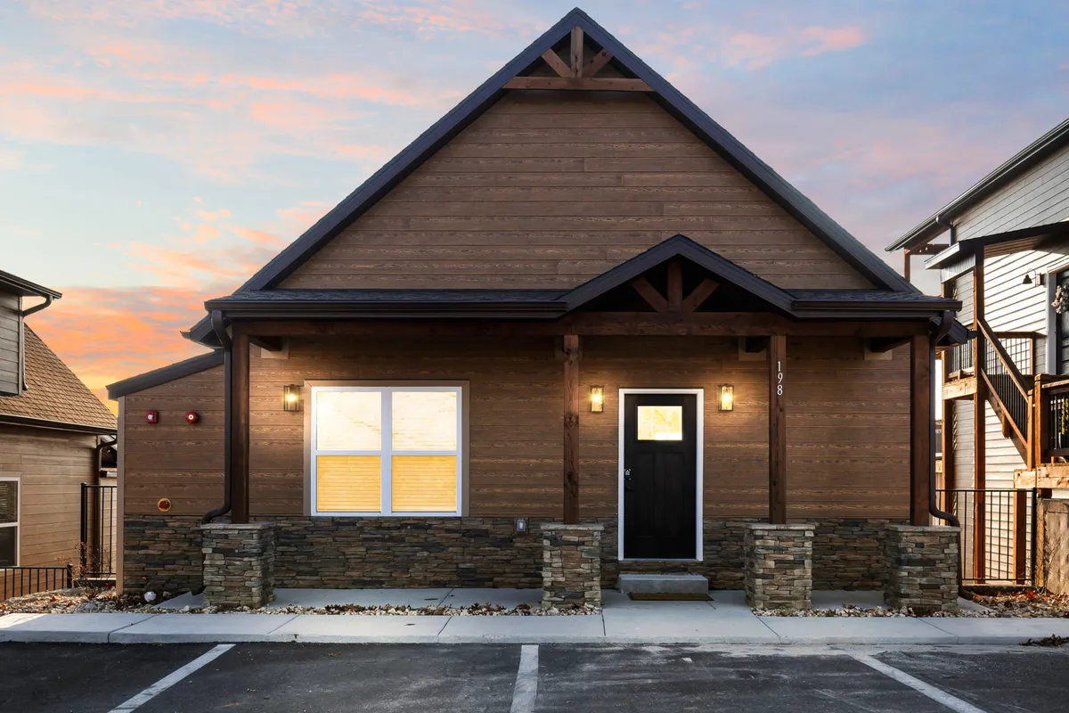This exterior image features the front door framed by stone pillars and a wooden facade, with welcoming outdoor spaces perfect for both people and their pets. The inviting porch area hints at easy access between the home and the surrounding grounds, making it ideal for guests with dogs.